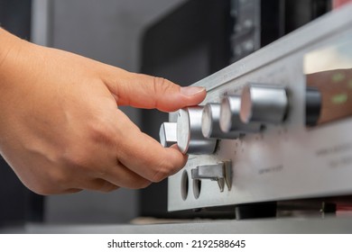 A Woman's Hand Turns The Volume Knob On The Home Audio System Amplifier.