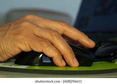 A woman's hand using a computer mouse, working in her office