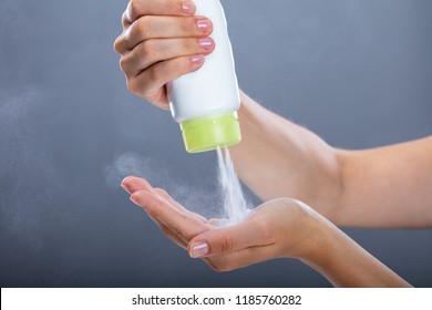 Woman's Hand Using Talcum Powder On Grey Background