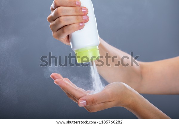 Woman\'s Hand\
Using Talcum Powder On Grey\
Background