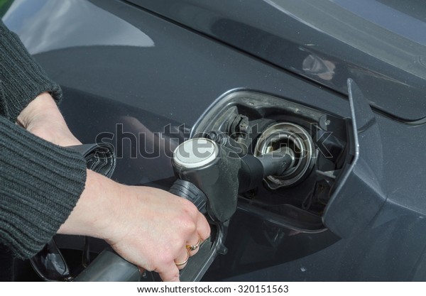 Woman\'s\
hand when fueling a sports car with fuel\
E10\
