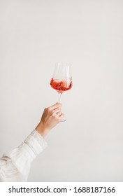 Die Frauen tragen ein weißes Hemd, das ein Glas Roswein hält und auf weißem Hintergrund dreht. Weinladen, Weinverkostung, Bar, Konzept der Weinliste