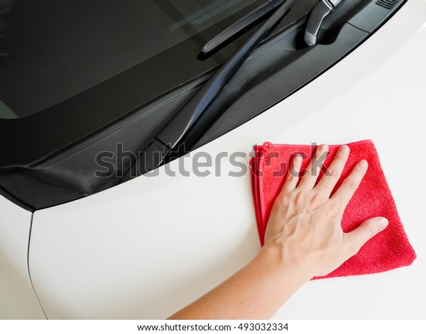 Woman\'s hand wiping a\
car with red cloth