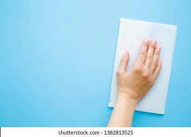 Woman's hand wiping pastel blue desk with white paper napkin. General or regular cleanup. Close up. Empty place for text or logo. - Shutterstock ID 1382813525