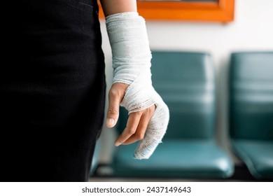 Woman's hand wrapped in white bandage from accident, injury, accident insurance, soft splint on finger, copy space - Powered by Shutterstock