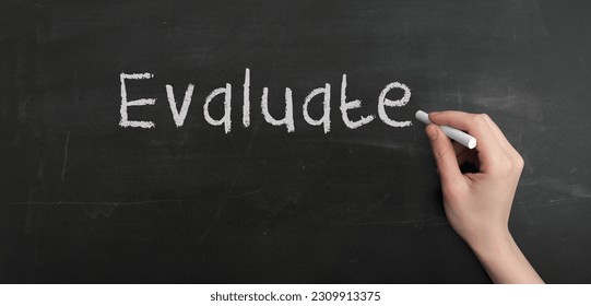 A woman's hand write text evaluate with chalk on chalkboard