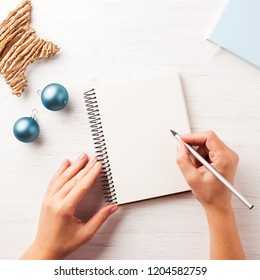 Woman's Hand Writing In Notebook On The Wooden Table. Top View.