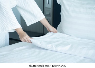 Woman's hands  adjusting a blanket in the bedroom hotel service. - Shutterstock ID 1239946429