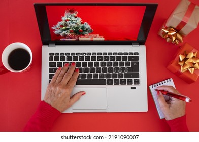 Woman's Hands Browsing On Laptop At Christmas Time - Red Background With Christmas Presents