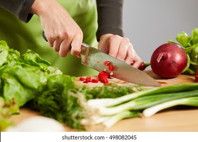 Woman's hands chopping vegetables on a wooden board