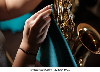 woman's hands cleaning a tenor saxophone with a cloth - Shutterstock ID 2230243921