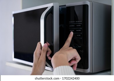Woman's hands closing the microwave oven door and preparing food in microwave.
