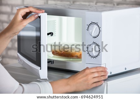 Woman's Hands Closing Microwave Oven Door And Preparing Food At Home