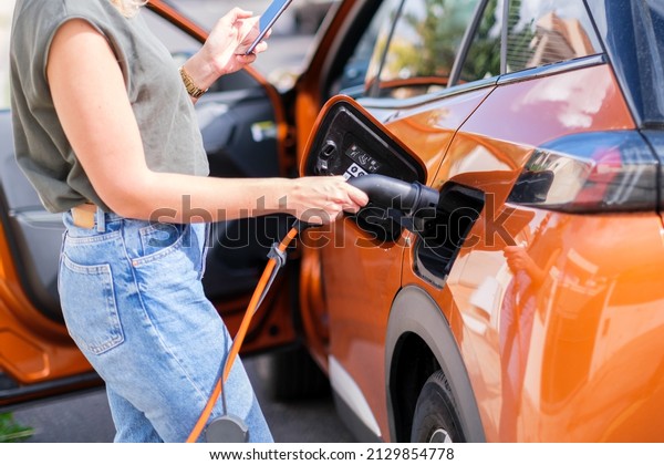 Woman\'s hands\
connecting the electric car\
charger