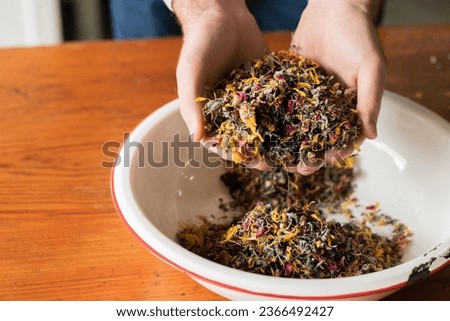 Woman's hands cradling a bowl of assorted tea leaves and herbs.