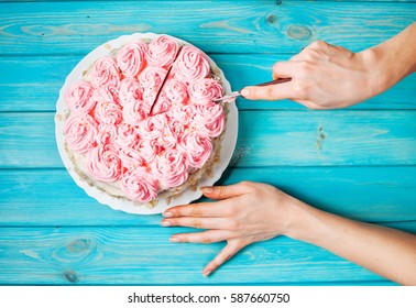 Woman's Hands Cut The Cake With Pink Cream On Blue Wood Background. Pink Cake. Top View