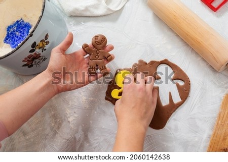 Woman's hands cut out cookies from the dough in the form of ginger man. Top view. Close-up of hands and a table with cookies. The concept of home cooking and Christmas.