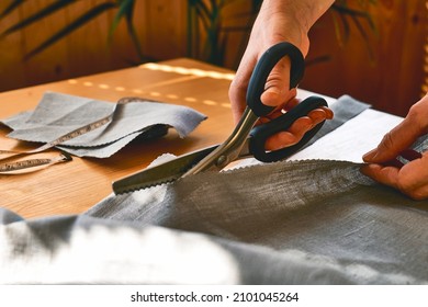 Woman's hands cutting out a pattern paper in linen fabric. Seamstress sewing on sewing machine in small studio. Fashion atelier, tailoring, handmade clothes concept.Soft focus. Defocused foreground. - Powered by Shutterstock