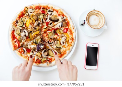 Woman's Hands With Dark Manicure Cutting Pizza, Cup Of Coffee And Mobile Phone On White Table, Flat Lay, Mock Up, Point Of View.