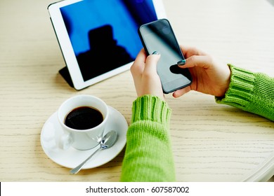 Woman's Hands With Dark Manicure Holding Mobile Phone, Tablet And Cup Of Coffee On Table, Freelance Concept, Online Shopping, Flat Lay.