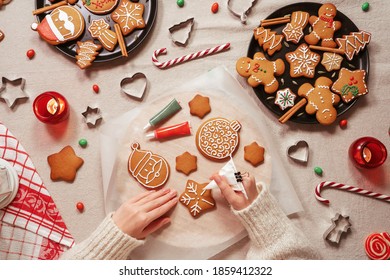 Woman's hands decorating a traditional gingerbread. Xmas flat lay. Christmas and New Year holidays mood. Top view of home table