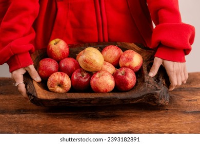 A woman's hands and fresh red apples arranged on a wooden surface convey the idea of a wholesome lifestyle, vegetarian principles, and the nutritional advantages gained from including fruits - Powered by Shutterstock