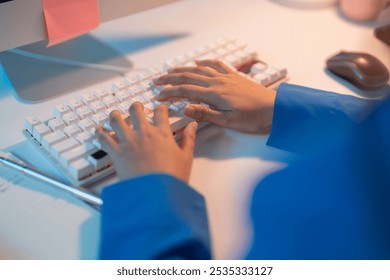 Woman's hands glow blue as she types on a mechanical keyboard late at night, focusing on coding work in a modern workspace filled with technology - Powered by Shutterstock