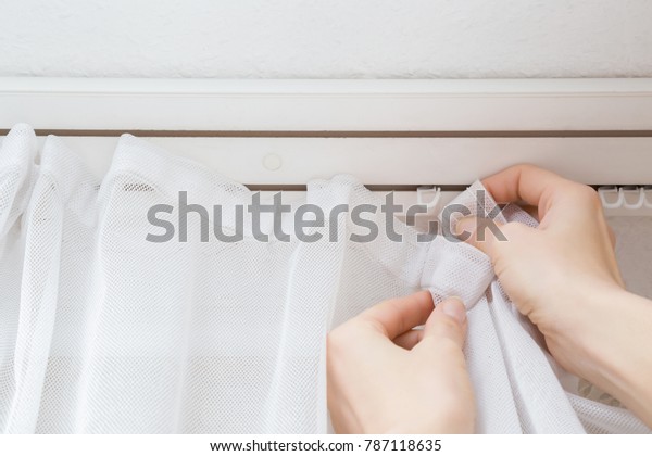 Woman\'s hands hanging washed\
and clean day\'s curtains at window in home. Cares about house\
concept.