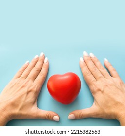 Woman's Hands And Heart On A Blue Background, Square Photo, Copyspace From Above. A Woman Keeps Love. Women's Health Protection. Cardiology, Heart Research. Prevention Of Stroke And Heart Attack