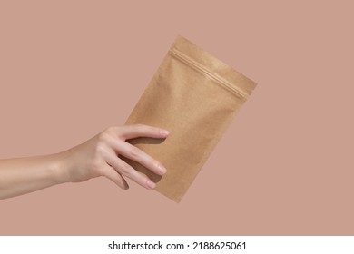 Woman's hands hold cardboard packages for tea or snacks on a beige background. Tea branding and packaging mockup. High quality photo