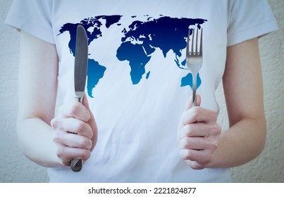 Woman's Hands Hold A Fork And Knife, Against The Backdrop Of A World Map. Concept Of Global Hunger.