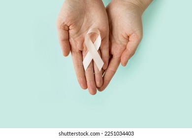 Woman's hands hold Peach Ribbon on blue background. Uterine Cancer Awareness month. Healthcare and World cancer day concept. - Powered by Shutterstock