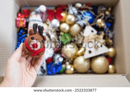 woman's hands holding box with vintage Christmas ornaments.