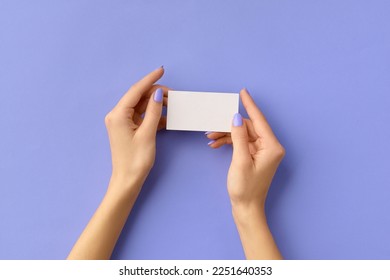 Womans hands holding business card on purple background. Business work template mockup