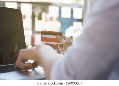 Woman's hands holding a credit card and using laptop computer for online shopping payment