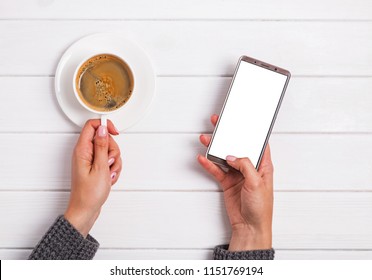 Woman's hands holding cup of coffee and using smarphone, top view - Powered by Shutterstock