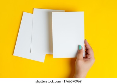 Woman's hands are holding empty mock-up brochure for writing letter above yellow background