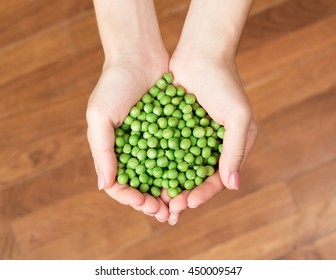 Woman's hands holding green peas. Heart shape from peas