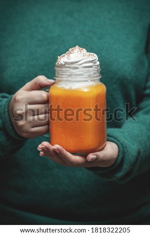 woman's hands holding a Mason jar with a pumpkin latte