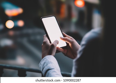 Woman's Hands Holding Mobile Phone With Lighted Big Copy Space Touch Screen Outdoors With Evening Bokeh Light Of City. Close Up View Of Female Person Using Smartphone App For Online Shopping