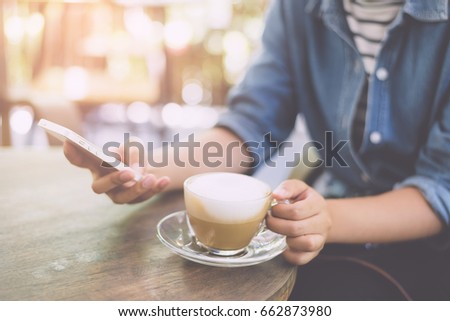 Womans hands holding smartphone at coffee shop