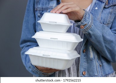 Woman's hands holding takeaway foam lunch boxes. Single use food containers, close up.