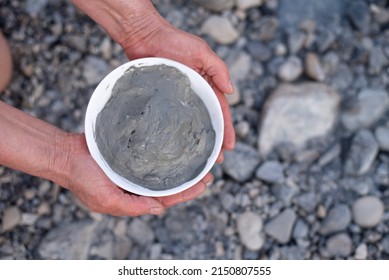 Woman's hands holds bowl with gray medical mud on rocky shore background. Healthy vacation on Dead Sea with therapeutic mud on face and body. Travel to hydrogen sulfur hot water in Israel - Shutterstock ID 2150807555