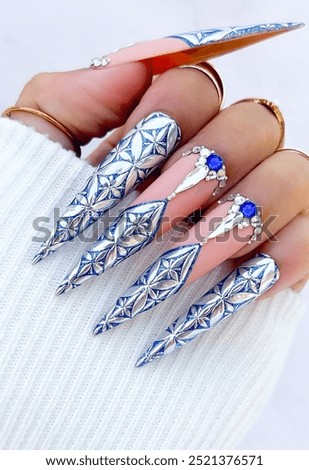 Woman's hands with long nails adorned with sparkling blue and white stones. Art nails. The concept of manicure and pedicure.