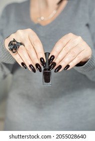 Woman's hands and long nails   black manicure and bottles nail polish