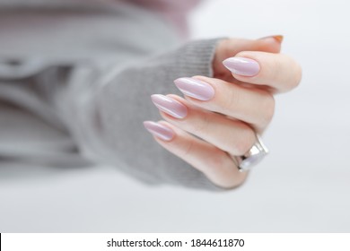 Woman's Hands With Long Nails And A Bottle Of Light Pink Color Nail Polish