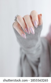 Woman's Hands With Long Nails And A Bottle Of Light Pink Color Nail Polish