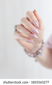 Woman's Hands With Long Nails And A Bottle Of Light Pink Color Nail Polish