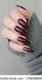 Woman's hands and long nails   dark red burgundy manicure holds bottle nail polish