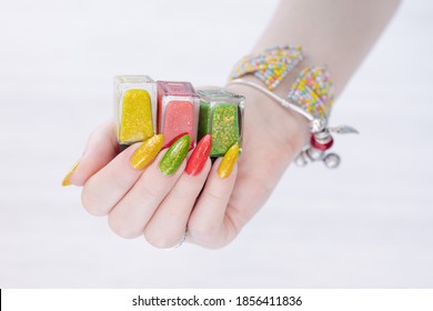 Woman's hands and long nails   multi  colored manicure  bottles nail polishes